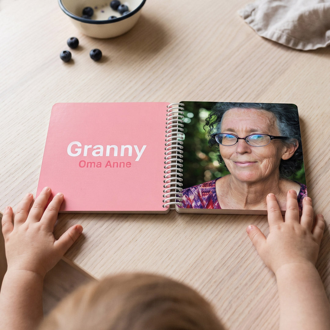 Fotobuch für internationale Familien aufgeschlagen, , wird von einem Kleinkind angeschaut, linke Seite Granny in großen Buchstaben, rechte Seite Foto von Granny
